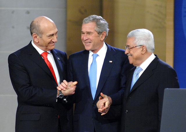 Israeli Prime Minister Ehud Omert, left, President George W. Bush, and Palestinian President Mahmoud Abbas shake hands at the Annapolis Conference, November 2008